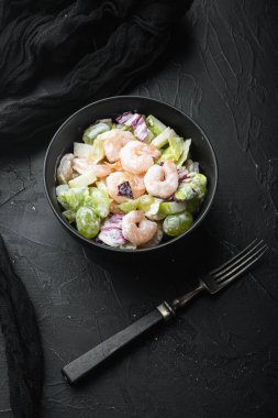 Karidesli salata, avokado, domates ve mayonez marul seti üzerinde, elma soslu ve üzümlü, siyah taş zemin üzerinde, en üstten düz görünüm