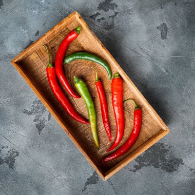 Kırmızı ve yeşil biber seti, ahşap kutuda, gri arka planda, üst manzara düz