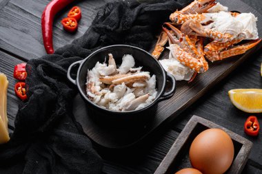 Kahvaltıda yengeç etli ve peynirli omlet için malzemeler, siyah ahşap masa arkasında.