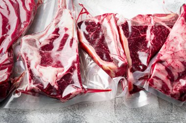 Biftek vakumu, pişirme seti, tomahawk, t bone, kulüp bifteği, pirzola ve fileto kesimleri için gri taştan arka planda hazır.