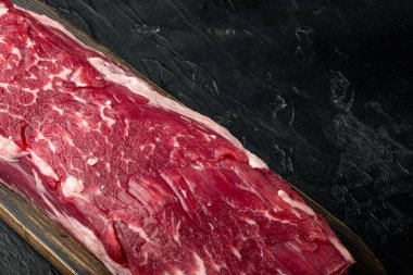 Taze ve çiğ et. Biftekli fileto parçasının tamamı siyah taş arka planda, metin için kopyalama alanı var.