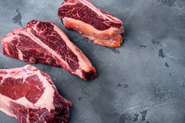 Çiğ Kara Angus Biftek seti, Tomahawk, kemik ya da biftek ve kulüp bifteği çeşitleri, gri taş arka planda, metin için kopyalama alanı ile