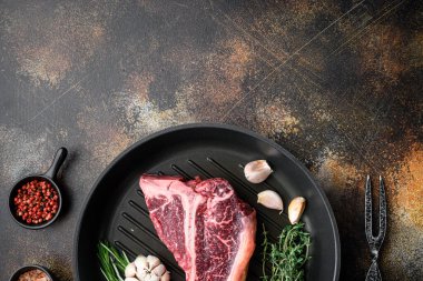 Çiğ kemik bifteği, malzeme seti, kızartma demir tava, eski koyu kırsal arka plan, üst manzara düz yatıyordu