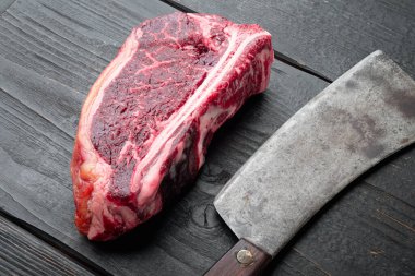 Taze, büyük ve iştah açıcı eski kulüp biftek seti, siyah ahşap masa arka planında.