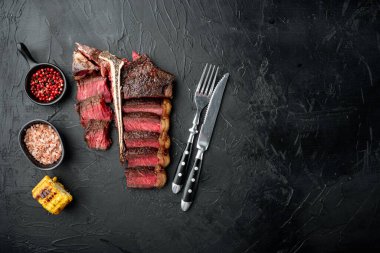 Taze sulu orta pişmiş biftek ve biftek ya da biftekli biftek seti, siyah taştan arka planda, düz manzaralı, metin için fotokopi alanı var.