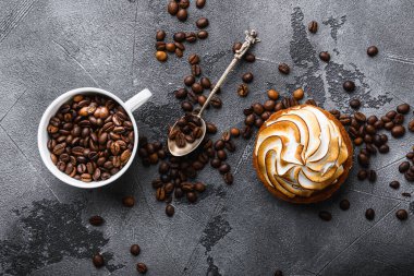 Kavrulmuş kahve çekirdekleri fincanda ve kek gri desenli arka plan, üst manzara..
