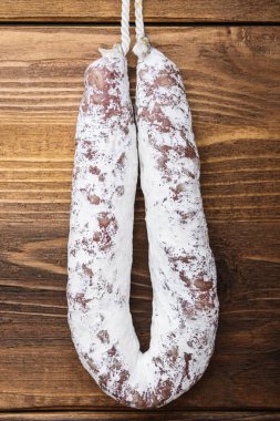 Hafif ahşap zemin üzerinde beyaz mayalanmış fuet sosisi, üst manzara.