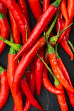 Uzun beslenmiş biber seti, siyah taş zemin üzerinde, üst görünüm düz yatıyordu