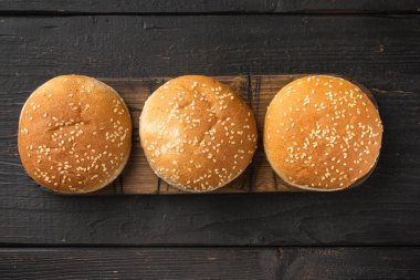 Hamburger ekmeği, ev yapımı Brioche Hamburger Çörekleri seti, ahşap servis tahtasına, siyah tahta masa arkasına, düz manzaralı, metin için fotokopi alanı olan