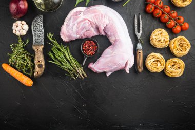 Çiğ tavşan taze sebzeli ve tavşan yahnisi için makarna seti, siyah taş arka planda, düz manzaralı, metin için fotokopi alanı ile