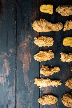 Koyu ahşap zemin üzerinde kızarmış tavuk parçaları, düz uzanmış, metin için yeri var..