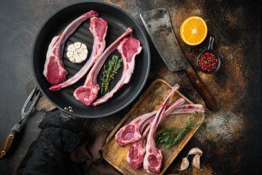 Çiğ taze kuzu fileto seti, malzemelerle birlikte, kızgın demir tavada, eski koyu kırsal arka planda, üst düz manzara