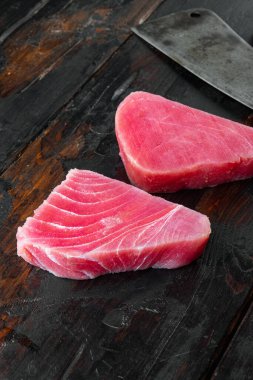 Çiğ ton balığı seti parçaları, ve eski kasap bıçağı, eski siyah ahşap masa arka planında