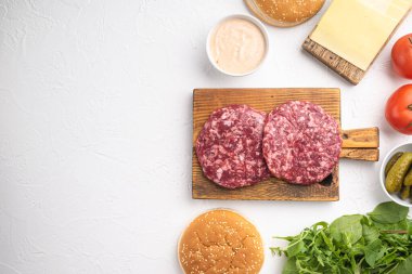 Beyaz taş zemin üzerine sığır burger malzemeleri seti, üst görünüm düz yatay, metin için kopyalama alanı ile