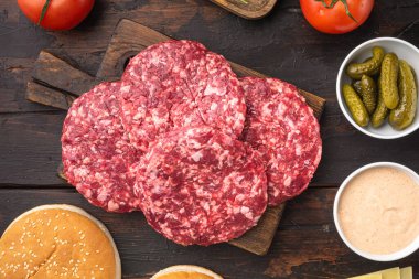 Hamburger seti için kıyma, eski koyu ahşap masa arkaplanı, üst manzara düz yatıyordu