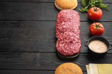 Hamburger pankartı. Hamburger seti için ham malzemeler, siyah ahşap masa arkaplanı, metin için kopyalama alanı