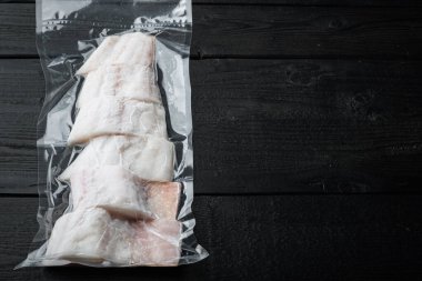 Martı beyaz balık fileto plastik market paketi, siyah ahşap masa üzerinde, metin için metin alanı ile üst görünüm