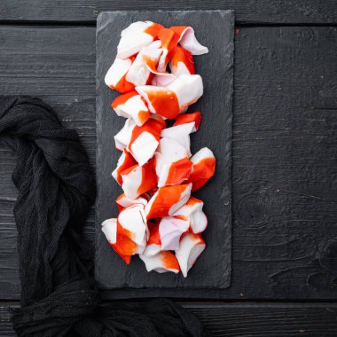 Mavi yüzme yengeci takımlı taze yengeç surimi, siyah ahşap masa arkaplanı, üst manzara düz.