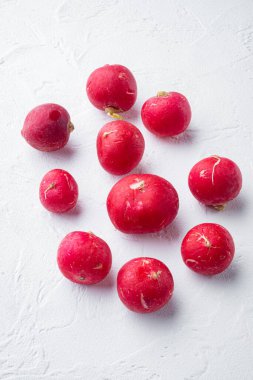 Beyaz arka planda kırmızı turpların etrafına sebze yığını.