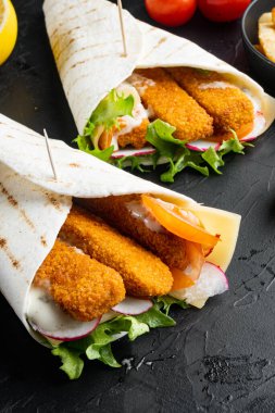 Balık kroket, peynir ve sebzeli tortilla rulosu, siyah arka planda.