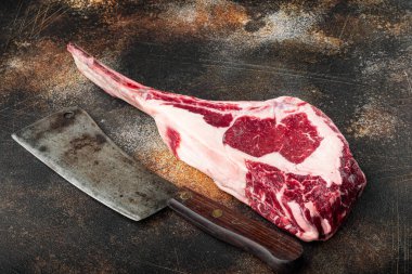 Çiğ taze tomahawk kuru mermer biftek seti, ve eski kasap satır bıçağı, eski koyu rustik arka planda, metin için kopyalama alanı ile