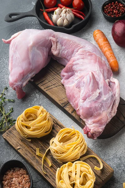 Çiğ taze tavşan yahni seti için kesilmiş, gri taş arka planda.