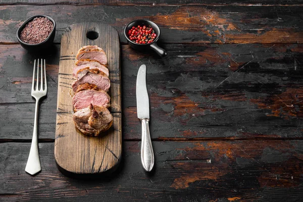 Grilled goose breast set, on wooden serving board, on old dark  wooden table background, with copyspace  and space for text