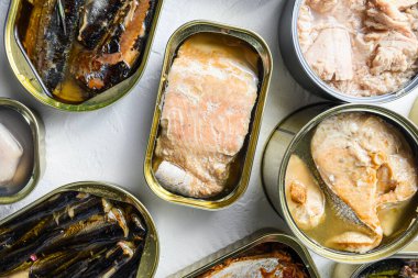 Alüminyum ve teneke kutuları Saury, uskumru, balık, sardalya, sardalya, sardalya, kalamar ve ton balığıyla birlikte beyaz desenli arkaplanı kapatın..