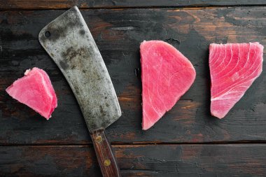 Çiğ ton balığı bifteği seti, ve eski kasap bıçağı, eski siyah ahşap masa arka planında, üst manzara düz yatıyordu