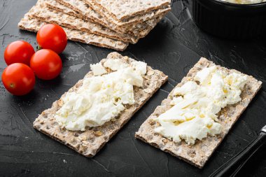 Taze çavdar gevrekleri, farklı bir malzeme setiyle, arka planda siyah taştan masa üzerinde.