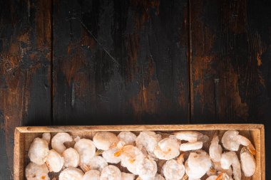 Donmuş soyulmuş karides seti, ahşap kutuda, eski siyah ahşap masa üzerinde, üst görünümü düz, metin alanı için kopyalama alanı ile