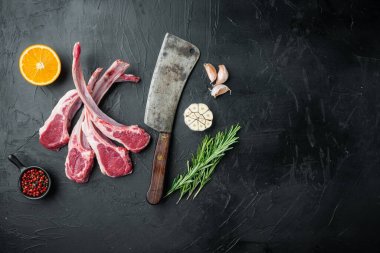 Taze kuzu pirzolası. Organik et seti, içeriği havuç portakalı, otlar, siyah taş zemin üzerinde, üst görünümü düz, metin için metin alanı ve yeri olan.