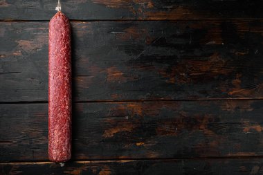 Geleneksel tütsülenmiş salam sosisi seti, eski koyu ahşap masa arkaplanı, üst görünüm düz, metin alanı için kopyalama alanı ile