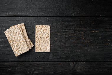 Ayçiçekli çıtır ekmek, chia ve susam tohumları seti, siyah ahşap masa arkaplanı üzerinde, üst görünüm düz, metin için kopya alanı ile