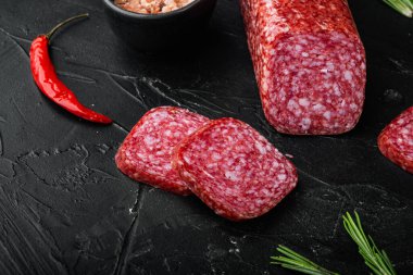 Salam, salam tütsülenmiş sosis, dilimlenmiş set, siyah koyu taş masa arkaplanı, metin için kopyalama alanı