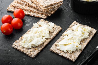 Taze çavdar gevrekleri, farklı bir malzeme setiyle, arka planda siyah taştan masa üzerinde.