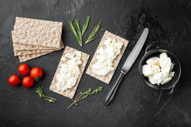 Taze otlu kremalı sandviçler. Süzme peynirli kızarmış ekmek, siyah taş masa zemininde, düz manzaralı.