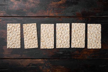 Ayçiçeği, chia ve susam tohumlu kepekli ekmek yığını, eski koyu ahşap masa arkaplanı üzerinde, üst görünüm düz, metin için kopya alanı ile