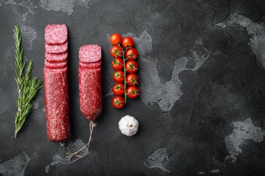 Bitki ve baharatlı salam, siyah taş masa arkaplanı üzerinde, üst görünüm düz, metin alanı için kopyalama alanı ile