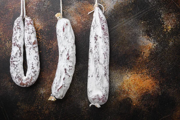 Kurutulmuş sucuk ve sosis koyu arkaplanda asılı..
