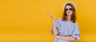 Dışarıdaki çekici kız öğrenci puanları. Avuç içi açık, sarı arka planda ciddi bir yüzü var.