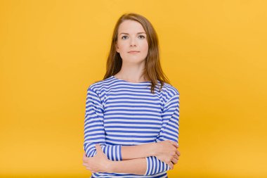 Kolları bağlı güzel bir kız öğrenci sarı arka planda kendini sakince soyutlanmış hissediyor. Doğal güzellik.