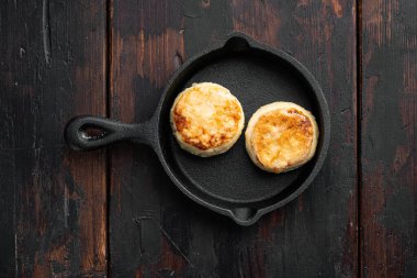 Syrniki Peynir krepleri dökme demir tavaya kurulmuş, üst görünüm düz, siyah ahşap masa zemininde, metin için kopyalama alanı ile