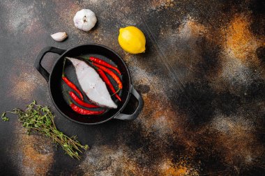 Çiğ halibut seti, malzemeler ve biberiye bitkileri ile, eski koyu rustik masa arka planı, üst görünüm düz, metin için kopyalama alanı ile