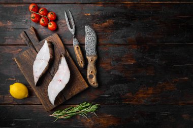 Beyaz balık seti çiğ biftek, malzemeler ve biberiye bitkileri, eski koyu ahşap masa arka planı, düz üst görünüm, metin için kopya alanı ile