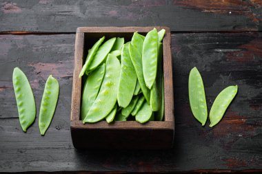 Sağlıklı bezelye seti, ahşap kutuda, eski, siyah ahşap masa arkasında.