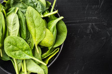 Taze ıspanak yaprakları hazır, kasede, siyah taş zemin üzerinde, üst görünüm düz, metin için kopyalama alanı var.