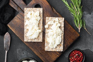 Taze otlu kremalı sandviçler. Süzme peynirli kızarmış ekmek, siyah taş masa zemininde, düz manzaralı.