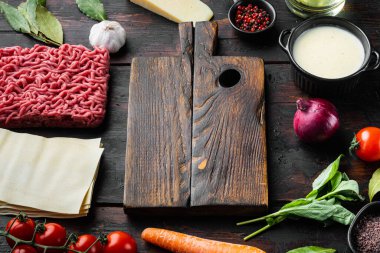 Boş alan temizleme tahtası lazanya pişirme konsepti. İtalyan Malzemeleri, lazanya çarşafları et bitkileri domatesler, beşamel sosu, eski koyu ahşap masa arkaplanı, metin için kopya alanı