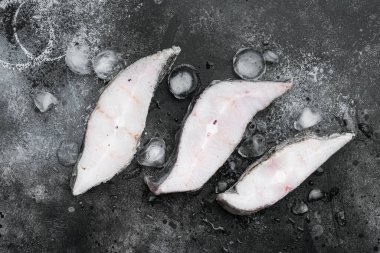 Donmuş balık bifteği seti, siyah taştan masa arkaplanı, üst manzara düz yatıyordu.